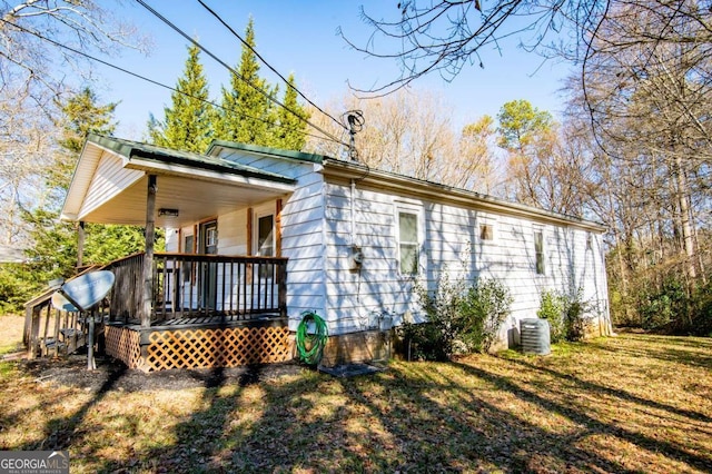 back of property with covered porch, cooling unit, and a lawn