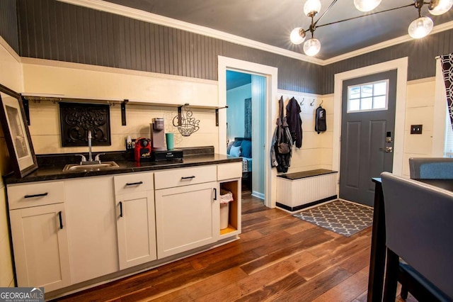 kitchen featuring white cabinetry, sink, hanging light fixtures, dark hardwood / wood-style floors, and ornamental molding