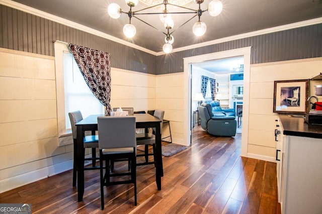 dining space featuring dark wood-type flooring, a notable chandelier, and ornamental molding