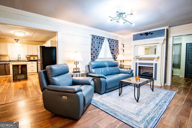 living room featuring hardwood / wood-style flooring, sink, and crown molding