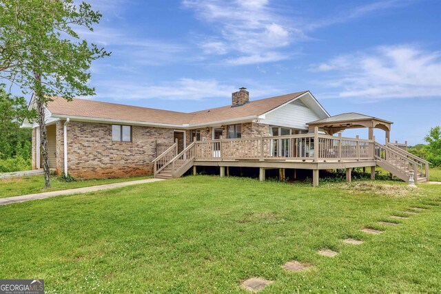 rear view of house featuring brick siding, a lawn, a chimney, and stairway