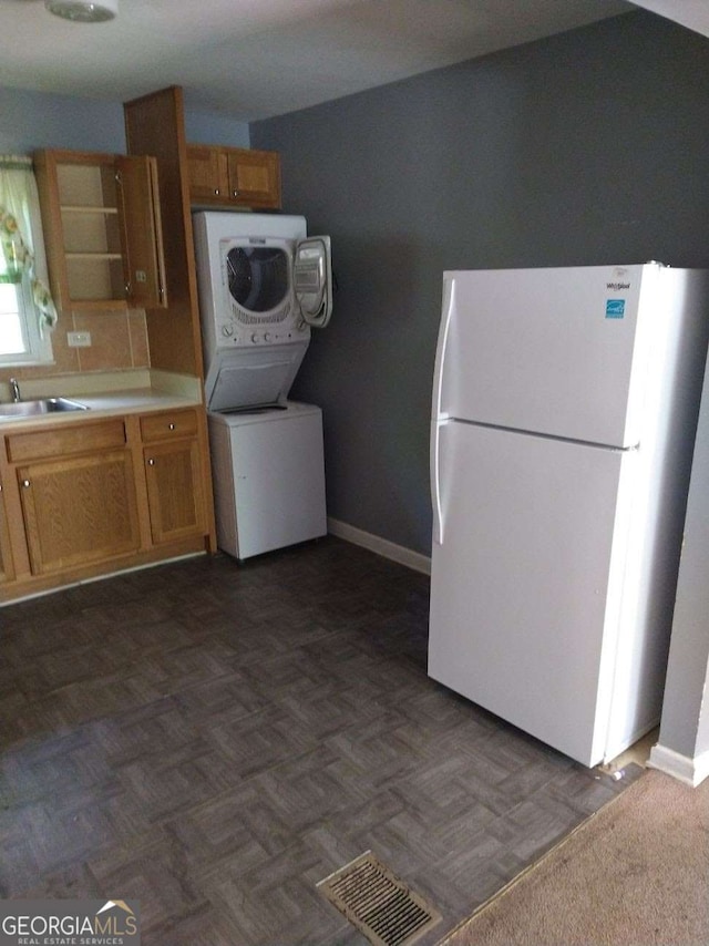 kitchen featuring white fridge, sink, and stacked washer and dryer