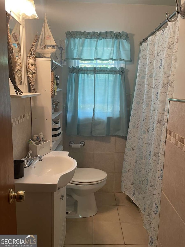 bathroom with tile patterned flooring, vanity, toilet, and tile walls