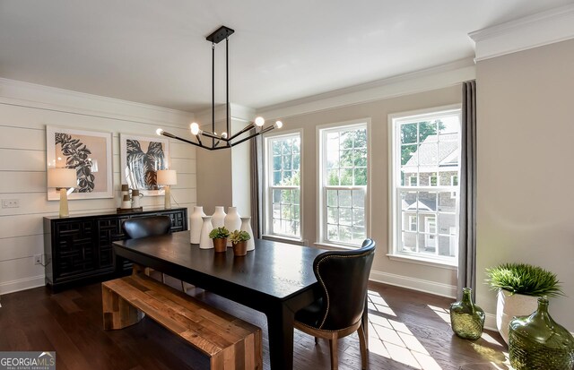 dining area with crown molding, dark wood-type flooring, and an inviting chandelier