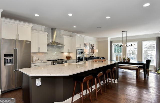 kitchen with stainless steel appliances, white cabinetry, wall chimney exhaust hood, and a large island