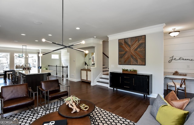 living room with dark hardwood / wood-style floors, ornamental molding, and a chandelier