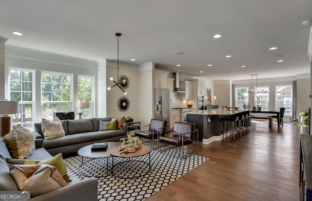 living room featuring crown molding, dark wood-type flooring, and a notable chandelier