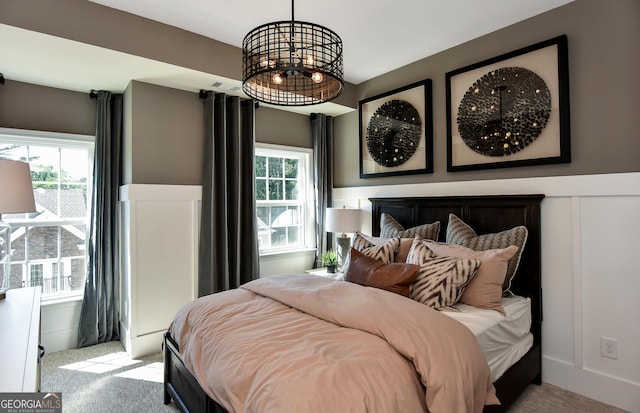 bedroom with an inviting chandelier, light colored carpet, and multiple windows