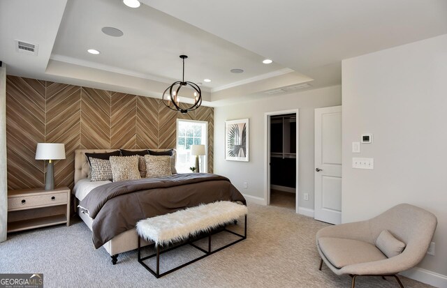 carpeted bedroom featuring a closet, a walk in closet, ornamental molding, and a tray ceiling