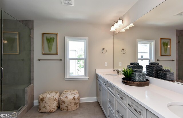 bathroom with plenty of natural light, vanity, a shower with shower door, and tile patterned flooring