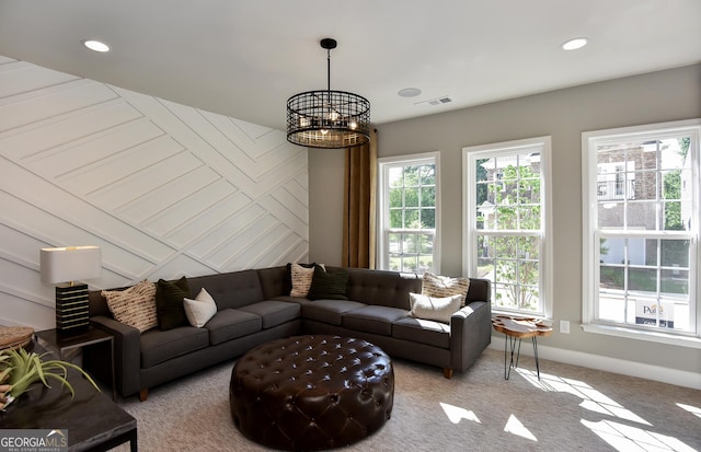 living room with plenty of natural light, light carpet, and an inviting chandelier