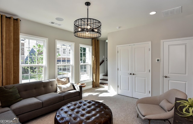 carpeted living room with an inviting chandelier