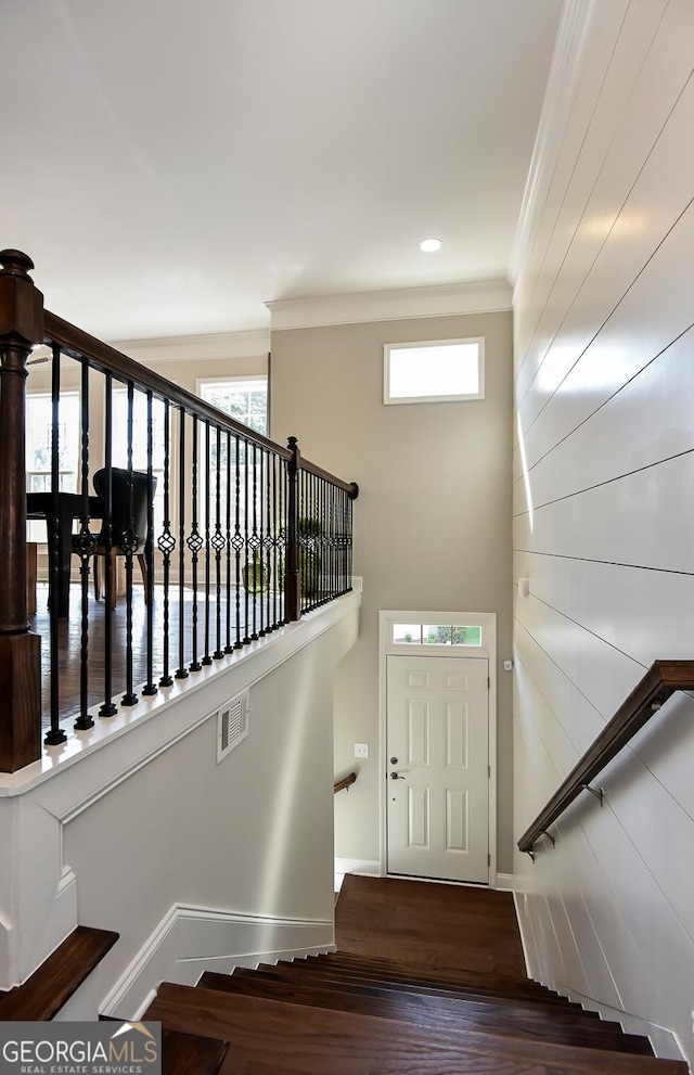 stairs featuring hardwood / wood-style floors, a wealth of natural light, and crown molding