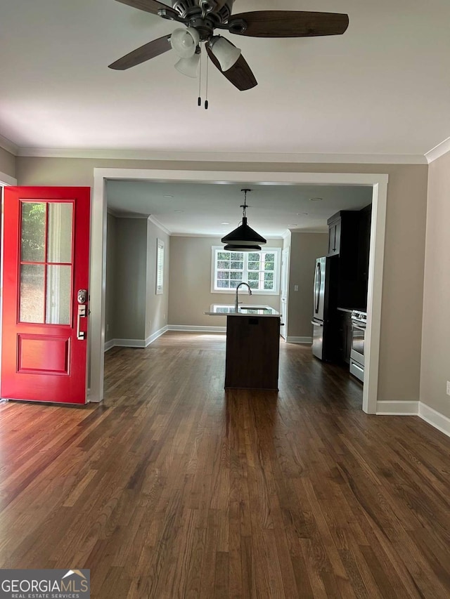 kitchen with crown molding, a center island with sink, stainless steel appliances, and dark hardwood / wood-style floors