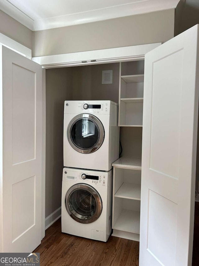 laundry room featuring dark hardwood / wood-style flooring and stacked washer and clothes dryer