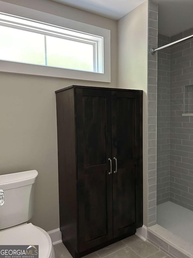 bathroom featuring a tile shower, toilet, and tile patterned floors