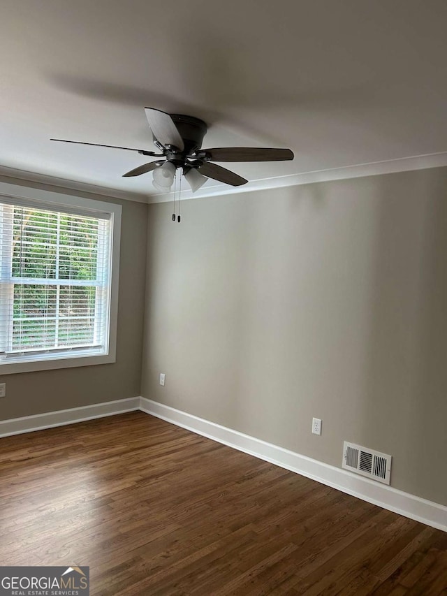 empty room with dark wood-type flooring, ceiling fan, and ornamental molding