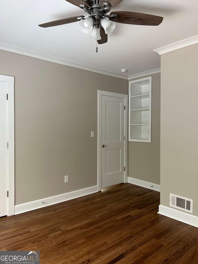 spare room with built in shelves, dark hardwood / wood-style flooring, ceiling fan, and ornamental molding