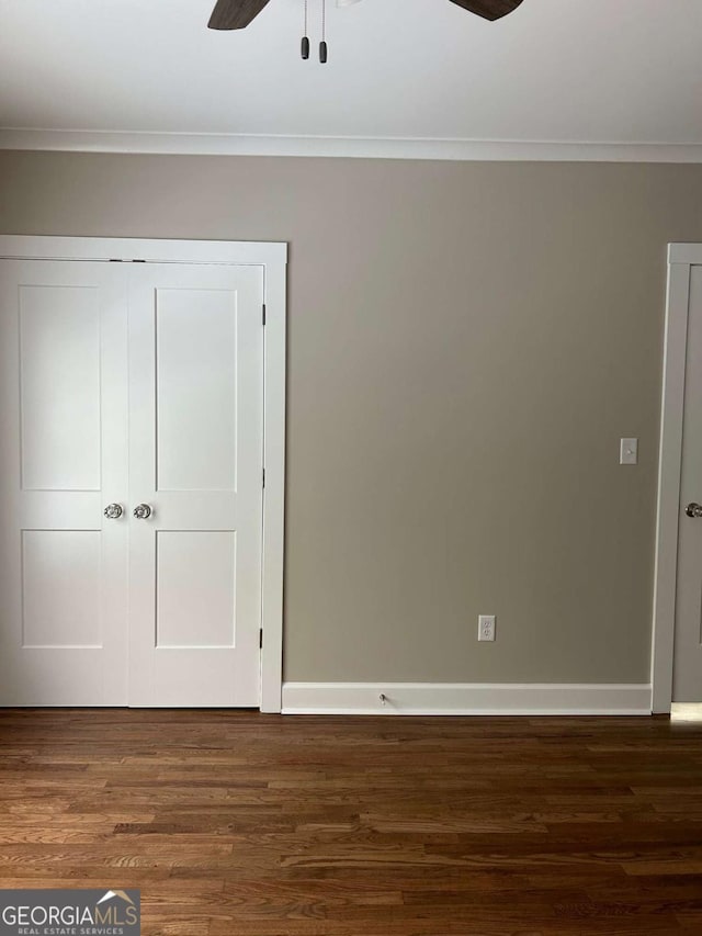 unfurnished bedroom featuring a closet, dark wood-type flooring, ceiling fan, and ornamental molding