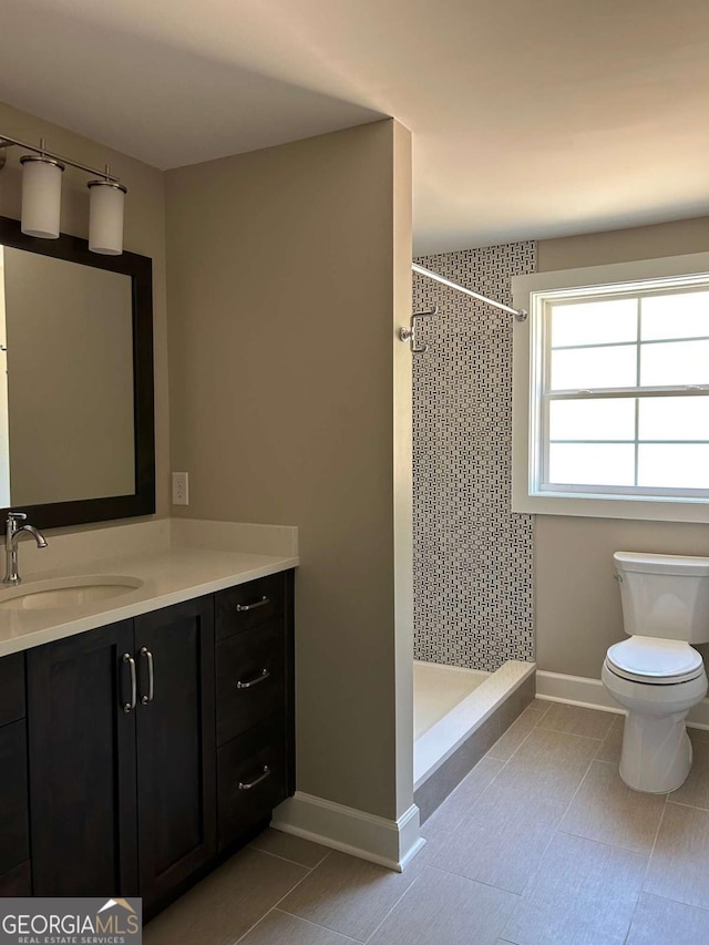 bathroom with toilet, vanity, and tiled shower