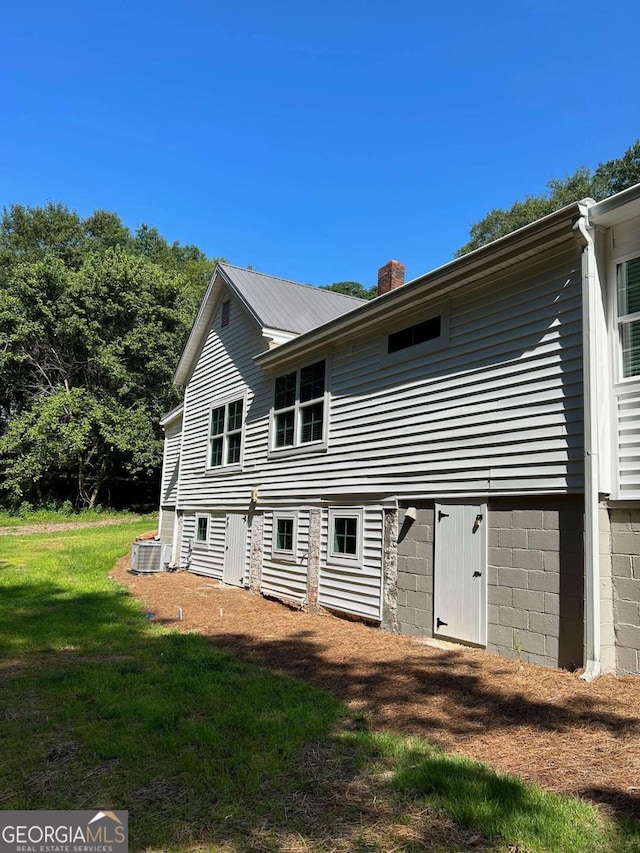 back of property with central AC and a lawn