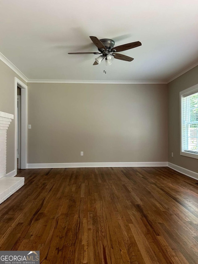 spare room with dark hardwood / wood-style floors, ceiling fan, crown molding, and a fireplace