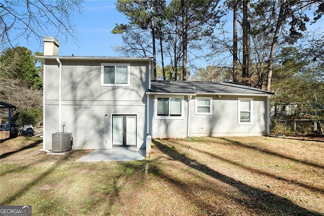 rear view of property with central air condition unit, a lawn, and a patio