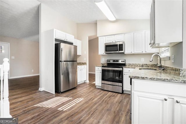 kitchen featuring light stone countertops, appliances with stainless steel finishes, sink, white cabinetry, and lofted ceiling