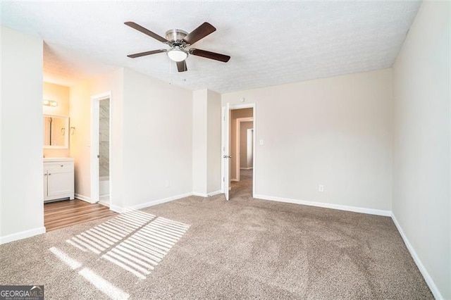 unfurnished bedroom featuring ceiling fan, light colored carpet, a textured ceiling, and ensuite bath