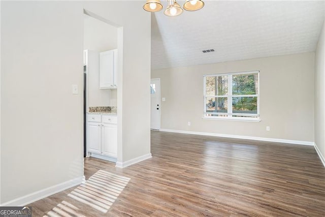 unfurnished living room featuring wood-type flooring and vaulted ceiling