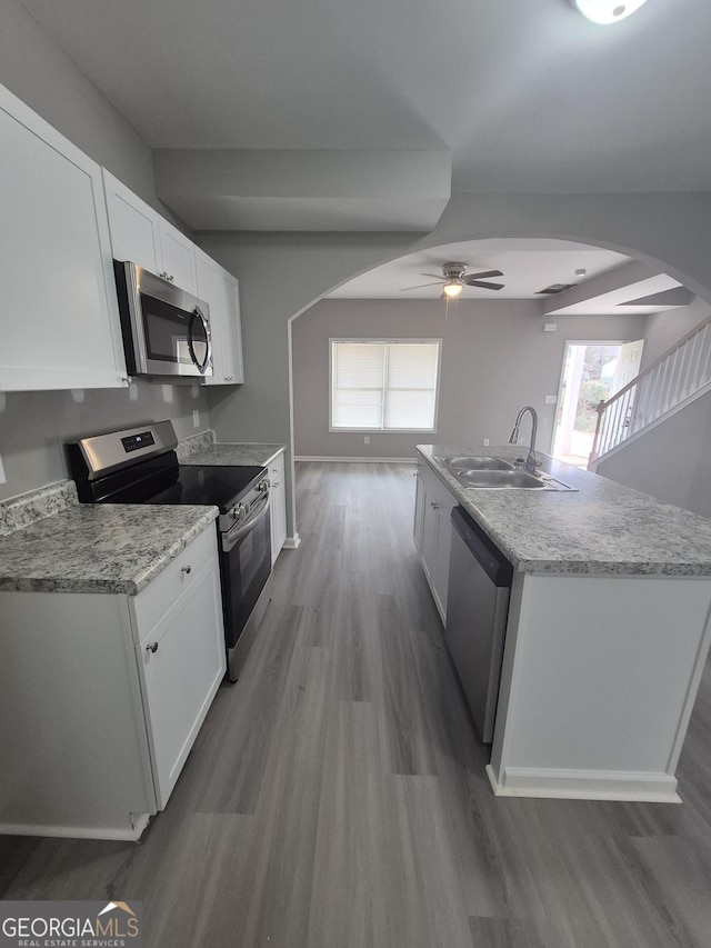 kitchen with sink, hardwood / wood-style flooring, ceiling fan, white cabinetry, and stainless steel appliances