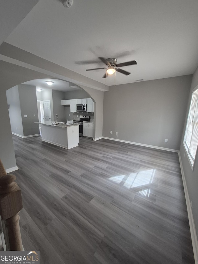 unfurnished living room featuring hardwood / wood-style flooring, ceiling fan, and sink