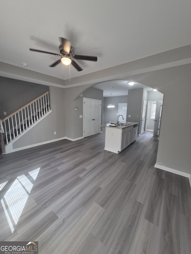 unfurnished living room with ceiling fan with notable chandelier, dark wood-type flooring, and sink