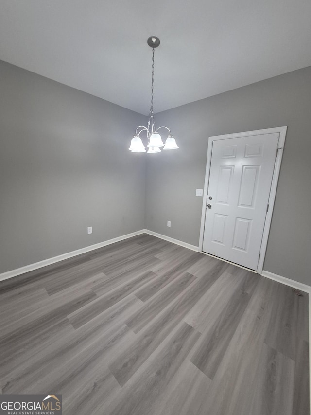 unfurnished dining area with a notable chandelier and wood-type flooring