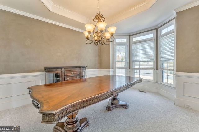 carpeted home office featuring a raised ceiling, crown molding, and an inviting chandelier