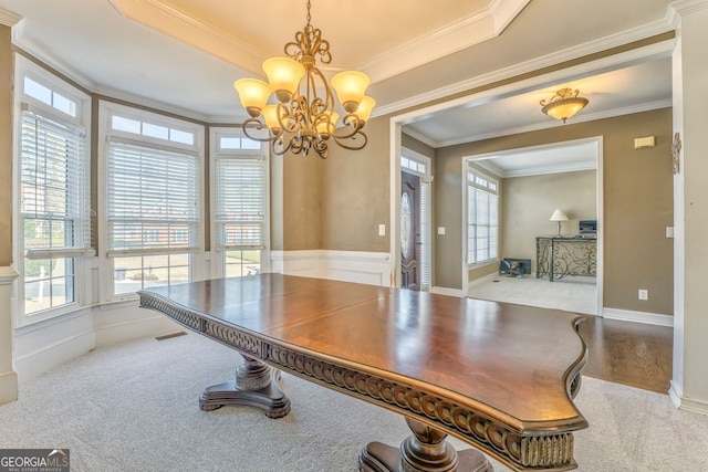 interior space with a raised ceiling, carpet, an inviting chandelier, and ornamental molding