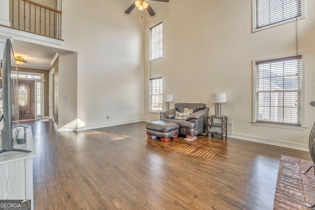 sitting room featuring ceiling fan, crown molding, a towering ceiling, and dark wood-type flooring