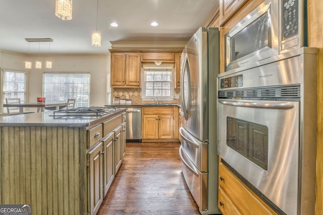 kitchen featuring tasteful backsplash, stainless steel appliances, sink, a kitchen island, and hanging light fixtures