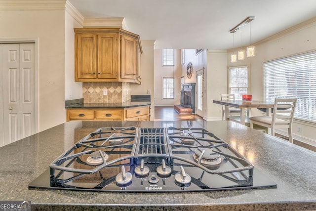 kitchen with cooktop, tasteful backsplash, hanging light fixtures, and ornamental molding