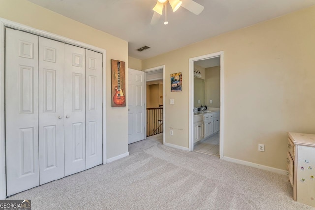 unfurnished bedroom with light carpet, a closet, ensuite bath, and ceiling fan