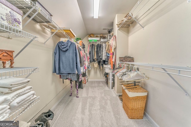 walk in closet featuring light colored carpet and lofted ceiling