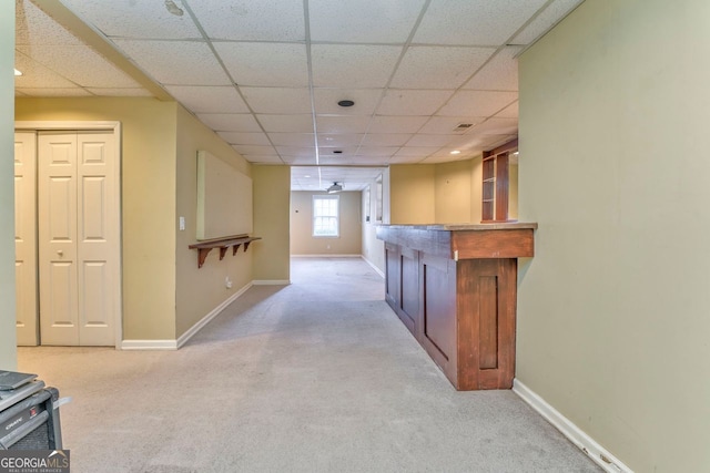 interior space with a paneled ceiling and light carpet