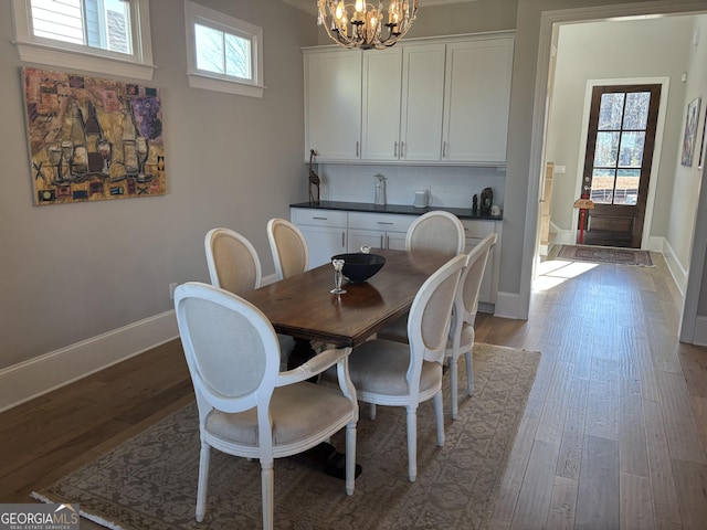 dining room featuring baseboards, wood-type flooring, a wealth of natural light, and an inviting chandelier