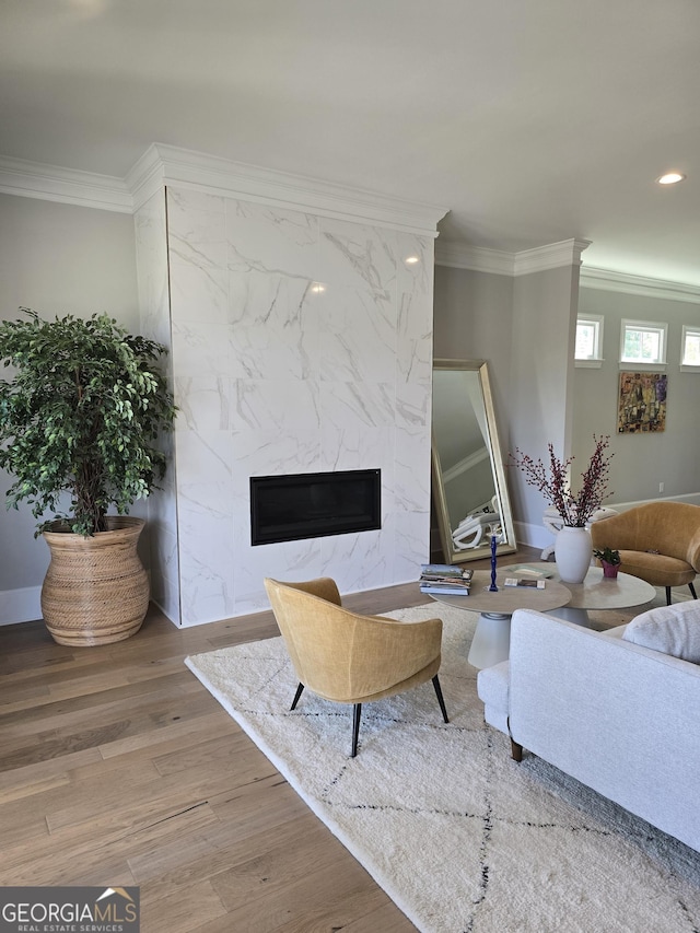 living room with recessed lighting, a premium fireplace, wood finished floors, baseboards, and ornamental molding