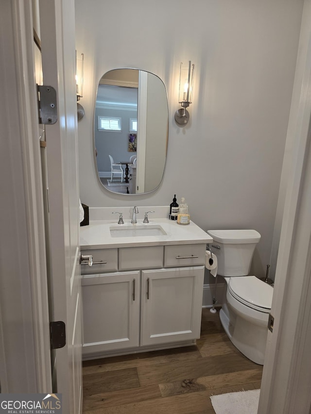 bathroom featuring vanity, wood finished floors, toilet, and baseboards