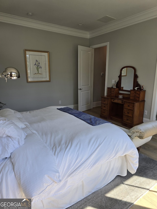 bedroom with crown molding, baseboards, and wood finished floors