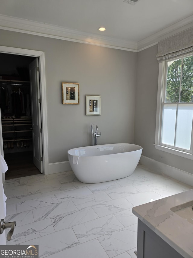 bathroom with baseboards, marble finish floor, crown molding, a freestanding tub, and recessed lighting