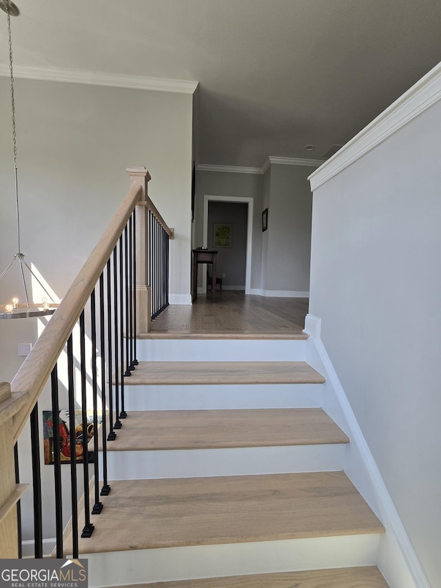 stairs featuring crown molding, baseboards, and a notable chandelier