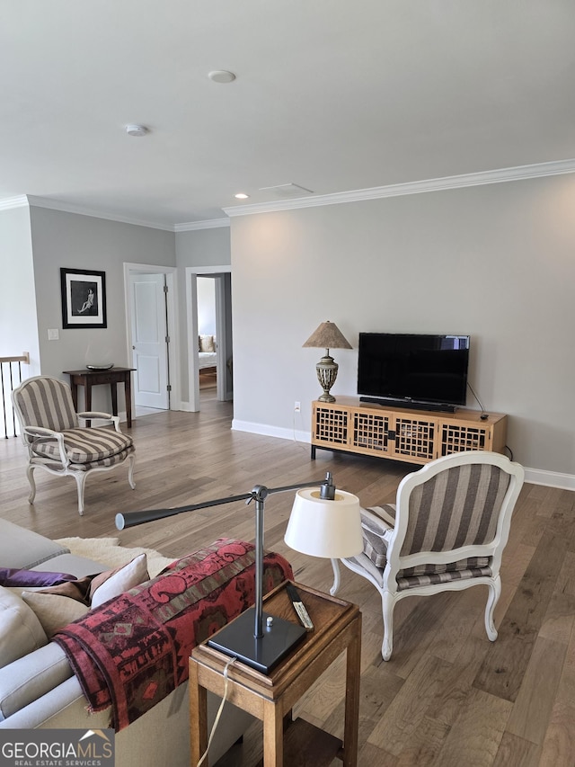 living area featuring ornamental molding, baseboards, and wood finished floors