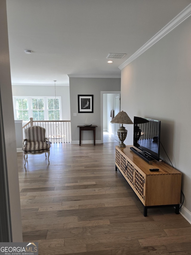 corridor featuring visible vents, crown molding, baseboards, and wood finished floors